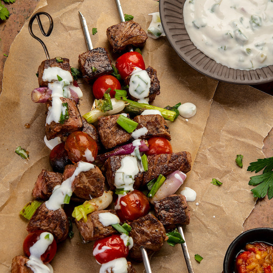 Skewers of grilled meat and vegetables with a side of yogurt sauce 