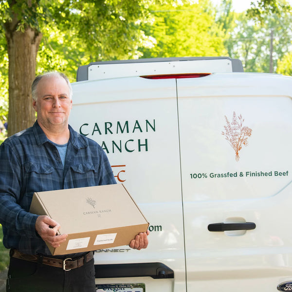 Man holding a box in front of a Carman Ranch truck
